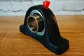 Mounted bearing housing with a red grease nipple cap applied to the lubrication fitting on top.