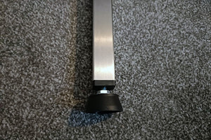 A black plastic threaded square tube insert with an adjustable foot attached. Fitted into a square metal tube.
