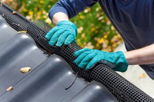 An arched plastic mesh, being fitted into a rain gutter.