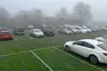 A temporary car park with grass growing through the plastic mesh and lines painted on top.