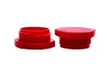 Two red plastic UNF threaded plugs. Both standing on opposite ends.
