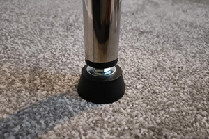 A chrome tube fitted with a black plastic threaded insert with an adjustable foot attached.