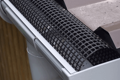 A metal roof and rain gutter. With an arched plastic mesh in the gutter.