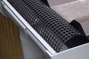 A metal roof and rain gutter. With an arched plastic mesh in the gutter.
