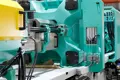 Injection moulding machine used for manufacturing plastic protective caps, showing the clamping unit, mould cavity area, and hydraulic components.