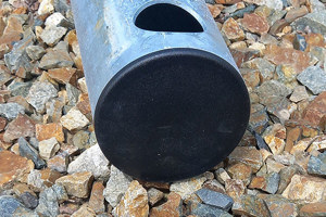 A round steel tube with a black plastic tube insert fitted in the end. Laying on gravel.