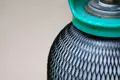 Close up of a gas cylinder covered in black plastic protective netting.