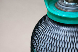 Close up of a gas cylinder covered in black plastic protective netting.