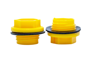Two Yellow plastic BSP threaded plugs with rubber sealing washers. Both standing on opposite ends.