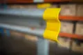 Flexible yellow pvc armco barrier cap fitted to armco section with blurred background.