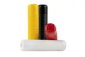 Angled side view of four ribbed industrial grips of different colours, yellow, black, white and red. Two upright and two on their side.