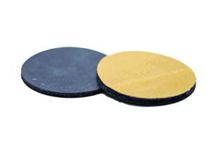 Two black, self adhesive rubber discs. One showing the rubber face and the other showing the adhesive backing.