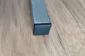 Top-down view of a black square injection-moulded insert foot fitted to the base of a metal tube leg.