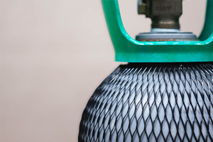 Close up of a gas cylinder covered in black plastic protective netting.