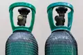 Two gas cylinders covered in black plastic protective netting.
