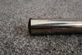 A black plastic round tube insert with a slightly domed top. Fitted into the end of a chrome tube.