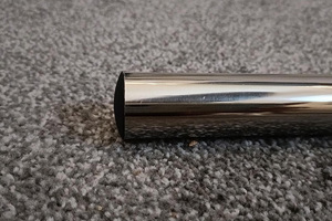 A black plastic round tube insert with a slightly domed top. Fitted into the end of a chrome tube.
