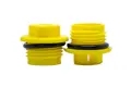 Two Yellow plastic BSP threaded plugs with rubber sealing O-Rings. Both standing on opposite ends.
