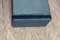 A black plastic rectangular tube insert. Fitted into the end of a rectangular metal tube.