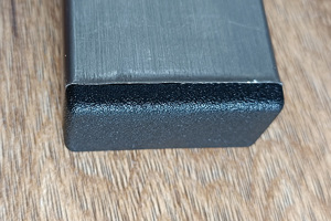 A black plastic rectangular tube insert. Fitted into the end of a rectangular metal tube.