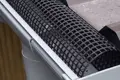 A metal roof and rain gutter. With an arched plastic mesh in the gutter.