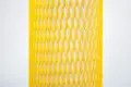 Yellow plastic protective netting, stretched over a tube.